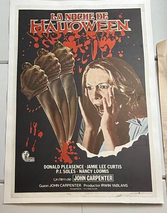 Vintage Halloween movie poster with a woman and hands holding knives on a dark background.