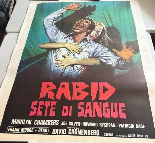 Vintage movie poster for 'Rabid Sete Di Sangue' with a dramatic scene of a man and woman, featuring bold text and intense colors.